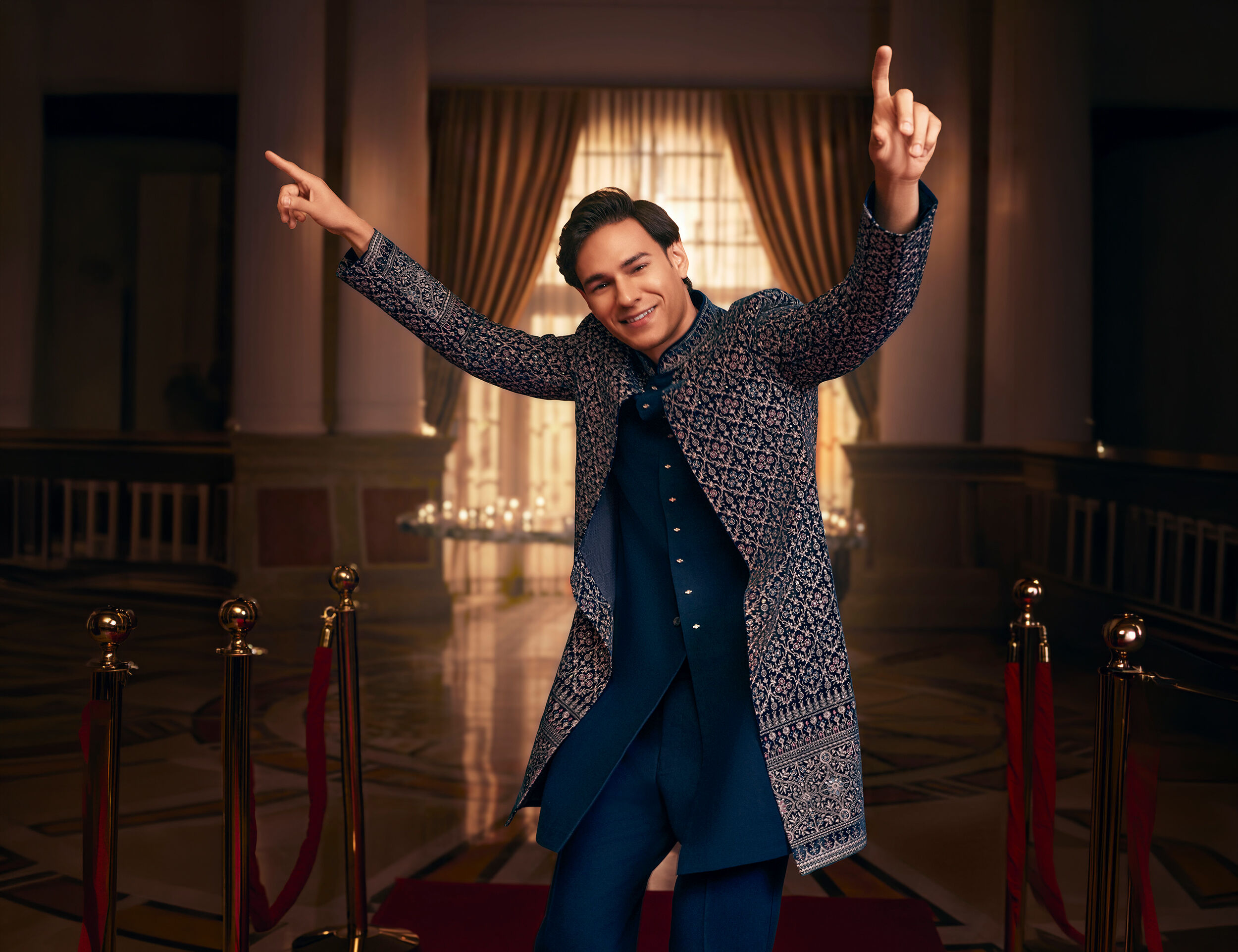 Man wearing a navy embroidered Jodhpuri wedding outfit in a grand indoor setting